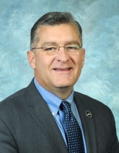 A man in suit and tie with glasses.