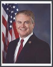 A man in suit and tie next to an american flag.